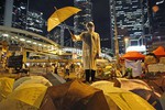 A protester holds an umbrella during a performance on a main road in the occupied areas outside government headquarters in Hong Kong's Admiralty in Hong Kong Thursday, Oct. 9, 2014.