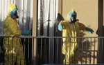 Hazardous material cleaners spray disinfectant on their personal protective equipment after working in the apartment where Thomas Eric Duncan, the Ebola patient who traveled from Liberia to Dallas, stayed last week, Sunday, Oct. 5, 2014, in Dallas.