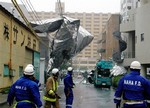  Firefighters from Naha Fire Department look up at a thin metallic object hanging from electric cables after it was apparently blown off a strong wind in Naha, Okinawa Prefecture (State), southwestern Japan, Friday, July 13, 2007. A powerful typhoon pound