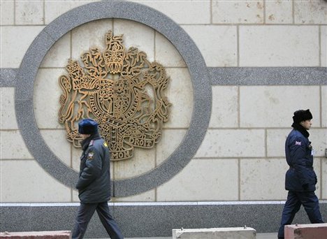 A Russian police officer walks along a wall, left, as a British security officer, right, guards the British Embassy building in Moscow on Wednesday, Dec. 6, 2006. Andrei Lugovoi, a key witness in the radiation poisoning case of former Russian agent Alexander Litvinenko, will meet with British investigators on Wednesday, a business associate said. Lugovoi traveled to London three times over the month before Litvinenko's death and met with Litvinenko four times, according to Russian media. 