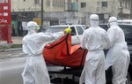 Health workers in protective gear load a body of a person suspected to have died from Ebola on the street of Monrovia ,Liberia. Monday, Oct. 13, 2014.