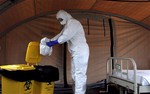 In this Thursday, Sept. 24, 2014 photo, nurse Dalila Martinez, trainer of the Cuban medical team to travel to Sierra Leone, practices proper disposal at a training camp, in Havana, Cuba.