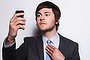 man using smart phone while adjusting necktie