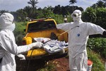 A health worker sprays disinfectant onto a college after they worked with the body of a man, suspected of contracting and dying form the Ebola virus on the outskirts of Monrovia, Liberia, Monday, Oct. 27, 2014.