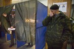 A pro-Russian rebel stands guard as a man leaves a voting cabin at a polling station during supreme council and presidential elections in the city of Donetsk, eastern Ukraine Sunday, Nov. 2, 2014.