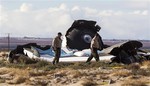 Law enforcement officials take a closer look at the wreckage near the site where a Virgin Galactic space tourism rocket, SpaceShipTwo, exploded and crashed in Mojave, Calif. Saturday, Nov 1, 2014.