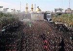 Shiite Muslim worshippers gather in front of the holy shrine of Imam Hussein, background, to mark Ashoura in the Shiite holy city of Karbala, 50 miles (80 kilometers) south of Baghdad, Iraq, Tuesday, Nov. 4, 2014.