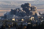 A bombs, seen top left, falls on an Islamic State position in eastern Kobani, during an airstrike by the US led coalition, seen from a hilltop outside Suruc, on the Turkey-Syria border Saturday, Nov. 8, 2014.