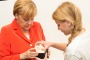 German Chancellor Angela Merkel tries out Esther Schulz's mood light as NICTA CEO Hugh Durrant-Whyte looks on.