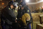 Police officers take a protester into custody Tuesday, Nov. 25, 2014, in Ferguson, Mo. Missouri's governor ordered hundreds more state militia into Ferguson on Tuesday, after a night of protests and rioting over a grand jury's decision not to indict police officer Darren Wilson in the fatal shooting of Michael Brown.