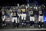 Members of the St. Louis Rams raise their arms in awareness of the events in Ferguson, Mo., as they walk onto the field during introductions before an NFL football game against the Oakland Raiders, Sunday, Nov. 30, 2014, in St. Louis.