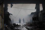 Firefighters examine burned-out market pavilions in central Grozny, Russia, Thursday, Dec. 4, 2014