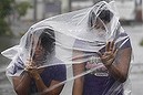 Filipino residents use plastic sheets to protect them from rains and strong winds brought by Typhoon Hagupit in Legazpi, Albay province, eastern Philippines on Sunday, Dec. 7, 2014. Typhoon Hagupit slammed into the central Philippines' east coast late Saturday, knocking out power and toppling trees in a region where 650,000 people have fled to safety, still haunted by the massive death and destruction wrought by a monster storm last year. (AP Photo/Aaron Favila)