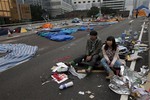 A couple sit at a main road before police clearing barricades and tents outside government headquarters in Hong Kong Thursday, Dec. 11, 2014.