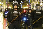 Police with wooden sticks stand guard, Monday, Dec. 8, 2014, after they cleared a group of protesters out who had stopped traffic at 4th and Pine in downtown Seattle during a demonstration against the decisions not to indict police officers who who killed men in Ferguson, Missouri and New York.