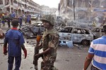 File - In this Wednesday, June, 25, 2014, file photo, a Nigerian soldier, center, walks, at the scene of an explosion in Abuja, Nigeria. Boko Haram, the Islamic extremist group whose birthplace is Maiduguri, is accused of a series of recent bomb attacks