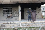 A member of the Kurdish forces holds up a piece of clothing worn by an Islamic State fighter found inside a makeshift base used in a battle in Kahrez, about 55 kilometers (34 miles) from Sinjar Mountain, Iraq, Thursday, Dec. 18, 2014.