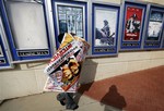 A poster for the movie "The Interview" is carried away by a worker after being pulled from a display case at a Carmike Cinemas movie theater, Wednesday, Dec. 17, 2014, in Atlanta.