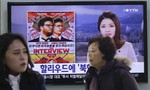 People walk past a TV screen showing a poster of Sony Picture's "The Interview" in a news report, at the Seoul Railway Station in Seoul, South Korea, Monday, Dec. 22, 2014.