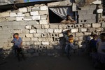 In this Tuesday, Oct. 1, 2013 photo, Majed Alwadiya, 31, watches children of his extended family members as they play outside their family house in Gaza City.