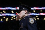 New York Police Department officer Jason Muller salutes during the national anthem after participating in a moment of silence for two slain NYPD officers before an NBA basketball game between the Brooklyn Nets and the Detroit Pistons