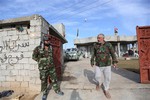 In this Saturday, Jan. 3, 2015 photo, Adnan Hassan, 59, right, and another Shiite militia member are seen outside a house they took over in Al-Rawashid a Sunni village outside the Iraqi city of Balad. 75 kilometers (45 miles) north of Baghdad, Iraq.