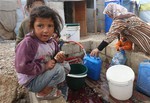 A Syrian girl eats a sandwich as others fill water containers at a refugee camp in Deir Zannoun village, Bekaa valley, Lebanon, Tuesday, Jan. 6, 2015.