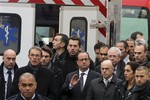 French President Francois Hollande, center, flanked with security forces gestures, as he arrives outside the French satirical newspaper Charlie Hebdo's office, in Paris, Wednesday, Jan. 7, 2015.