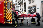 An injured person is transported to an ambulance after a shooting, at the French satirical newspaper Charlie Hebdo's office, in Paris, Wednesday, Jan. 7, 2015