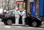 Forensic experts examine the car believed to have been used as the escape vehicle by gunmen who attacked the French satirical newspaper Charlie Hebdo's office, in Paris, France, Wednesday, Jan. 7, 2015.