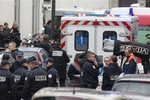 Police officers and rescue workers gather at the scene after gunmen stormed a French newspaper, killing at least 12 people, in Paris, Wednesday, Jan. 7, 2015. Masked gunmen shouting "Allahu akbar!" stormed the Paris offices of the satirical newspaper Charlie Hebdo, killing 12 people.