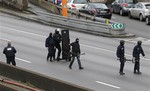 Hooded police officers walk on the closed ring road that circles Paris near a hostage-taking situation at a kosher market in Paris, Friday Jan.9, 2015.