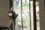 A police officer closes the bullet ridden door next to a body lying in the kosher market, in Paris, Friday Jan. 9, 2015.