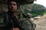 File - A member of the Afghan National Army calls for help as a member of the Afghan Border Police fires at Anti Afghanistan Forces in the mountains surrounding Barge Matal in Afghanistan’s eastern Nuristan province, during Operation Mountain Fire.