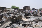 File - In this Sunday, May 11, 2014 file photo, people stand outside burnt houses following an attack by Islamic militants Boko Haram in Gambaru, Nigeria.