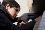 In this Wednesday, Nov. 19, 2014 photo, a female Kurdish fighter takes aim in Kobani, Syria. Kurdish fighters backed by intense U.S.-led airstrikes pushed the Islamic State group almost entirely out of the Syrian town of Kobani on Monday, Jan. 26, 2015.