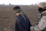 File - An Iraqi army soldier from 2nd Platoon Charlie Company 1st Battalion 1st Brigade 4th Infantry Division escorts a detainee captured during an early morning raid of Bayji Island, Iraq on 15 January 2006.