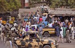 Nigerian soldiers, left, pass on the back of a armed truck as they patrol at a local market Tuesday, Jan. 27, 2015, after recent violence in surrounding areas at Maiduguri, Nigeria. I