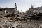 File - In this Nov. 19, 2014 photo, a Kurdish fighter shows the extent of the damage from a truck bomb in Kobani, Syria.