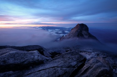 Mount Kinabalu is one of prominent mountains in Southeast Asia and is 
deeply revered by the locals. We started the climb early morning and 
got up there just before sunrise. It was very misty that morning and I 
was thinking I wouldn't get much good photos; but the mist in 
combination of the beautiful dawn colours made this picture one of my 
favourite from the trip.