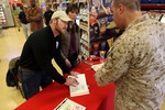 File - Navy Seal Sniper Chris Kyle signs a copy of his new book “American Sniper” for a Camp Pendleton sailor at the base’s Country Store, Jan. 13, 2012.