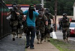 In this Aug. 11, 2014, file photo, police wearing riot gear walk toward a man with his hands raised in Ferguson, Mo.