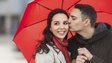 man kissing woman while holding umbrella for her