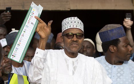 Opposition candidate Gen. Muhammadu Buhari holds his ballot paper in the air before casting his vote in his home town of Daura, northern Nigeria Saturday, March 28, 2015.