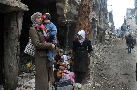 In this Tuesday, Feb. 4, 2014 file photo, released by the Syrian official news agency SANA, residents of the besieged Yarmouk Palestinian refugee camp wait to leave the camp, on the southern edge of the Syrian capital Damascus, Syria.