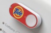 A Tide-branded Amazon Dash button, attached to a washing machine, allows re-ordering of detergent with a single press.