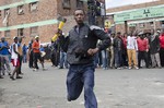 A man armed with an axe threatens members of the press in Johannesburg, Friday, April 17, 2015 after overnight attacks between locals and immigrants in Johannesburg. Several shops and cars were torched overnight in continued anti-immigrant attacks by locals.