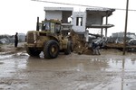 Palestinians, whose houses were destroyed by what they said was Israeli shelling during a 50- day-war last summer, use a bulldozer to remove rubbles on a stormy day in the east of Khan Younis in the southern Gaza Strip.