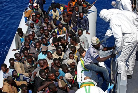 In this photo made available Thursday, April 23, 2015, migrants crowd an inflatable dinghy as rescue vassel " Denaro " of the Italian Coast Guard approaches them, off the Libyan coast, in the Mediterranean Sea, Wednesday, April 22, 2015.