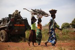 File - Women carrying wood walk past a French military patrol 10 kms south of Yaloke, north of Bangui, Central African Republic, Monday Feb. 10, 2014.